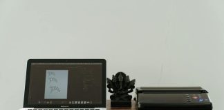 A creative home office setup featuring a laptop, printer, and artistic design work.