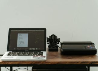 A creative home office setup featuring a laptop, printer, and artistic design work.
