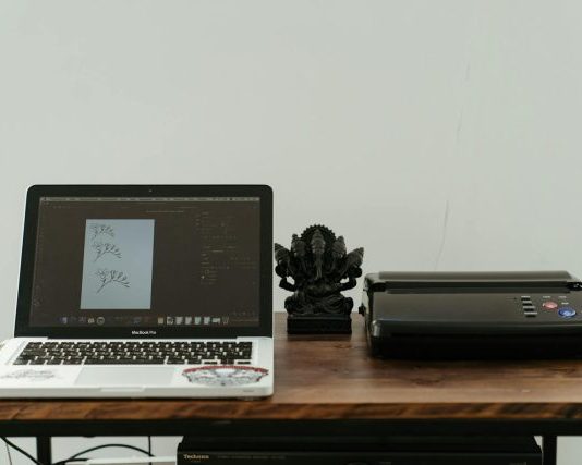 A creative home office setup featuring a laptop, printer, and artistic design work.
