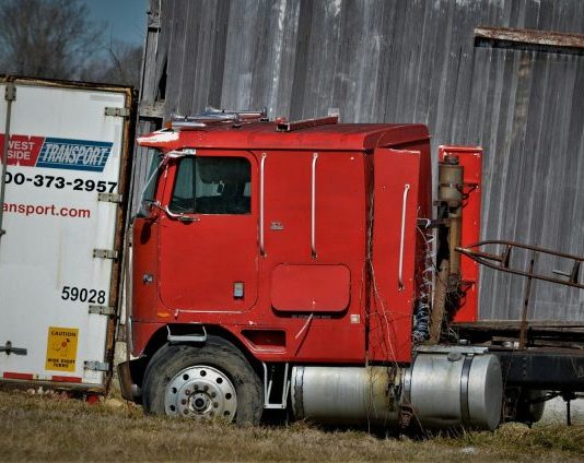red and white freight truck on green grass field during daytime