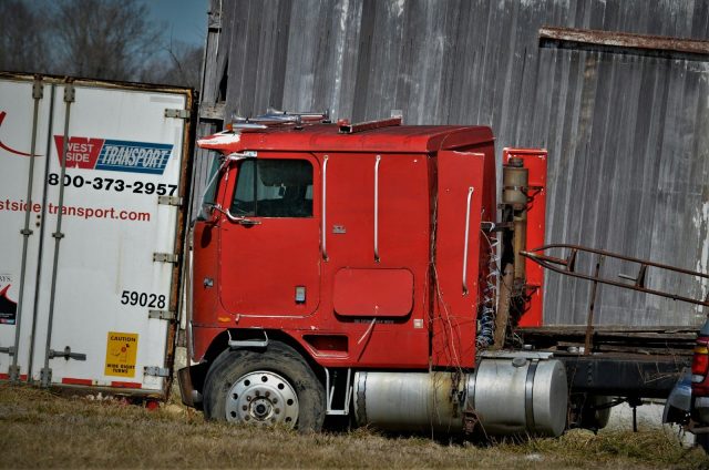 red and white freight truck on green grass field during daytime