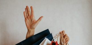 Person waving from behind shopping bags