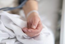 a person with a bandage on their hand sitting on a bed