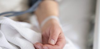 a person with a bandage on their hand sitting on a bed